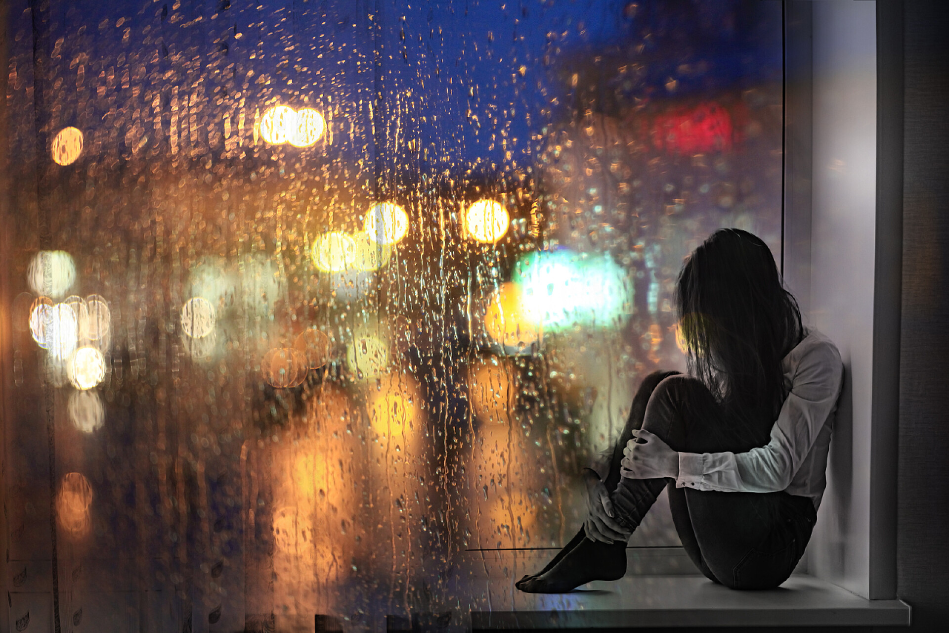 一个少女坐在家里的玻璃窗台上独孤难过伤心哭泣