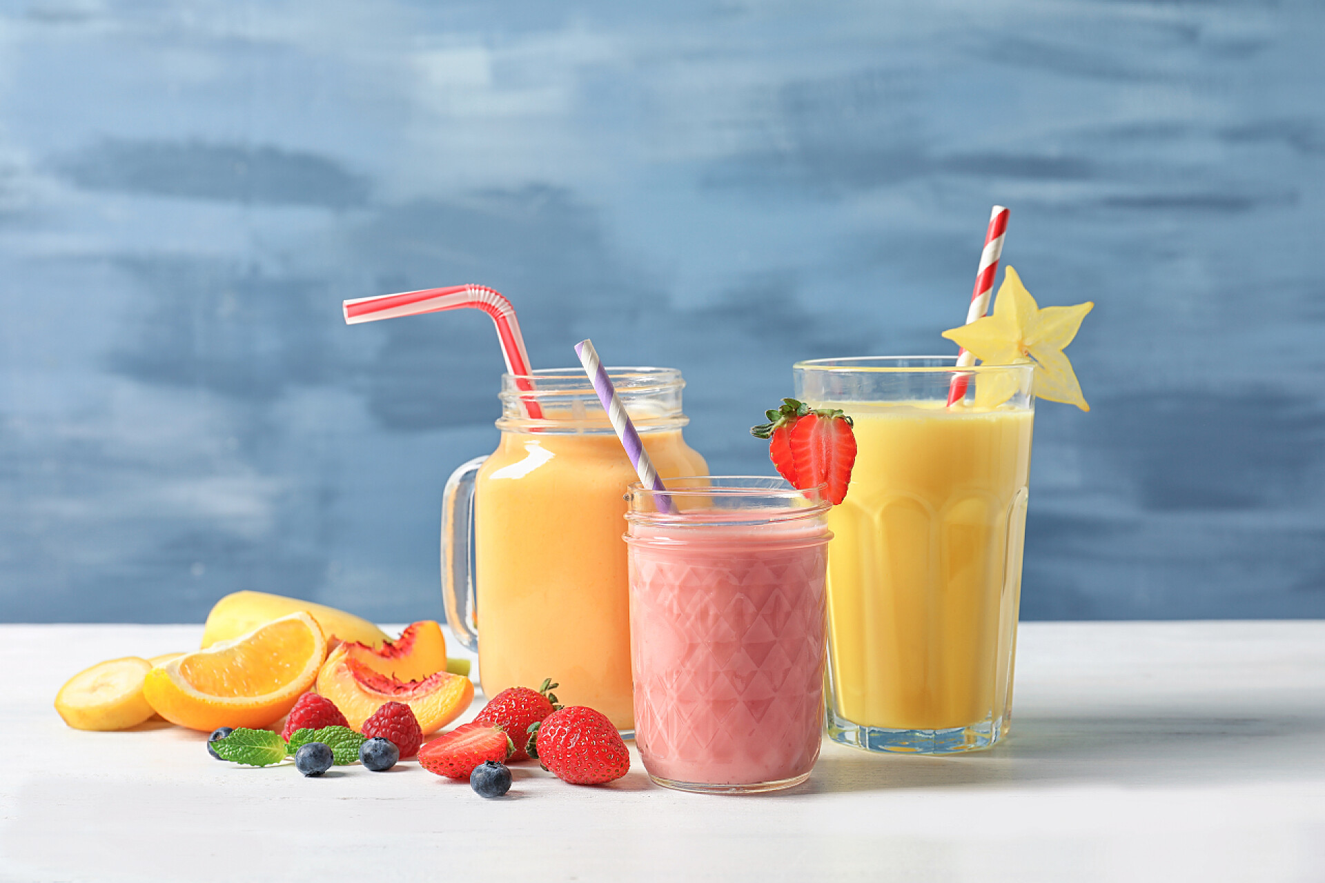 饮品桌上摆放的橙子草莓蓝莓水果奶昔