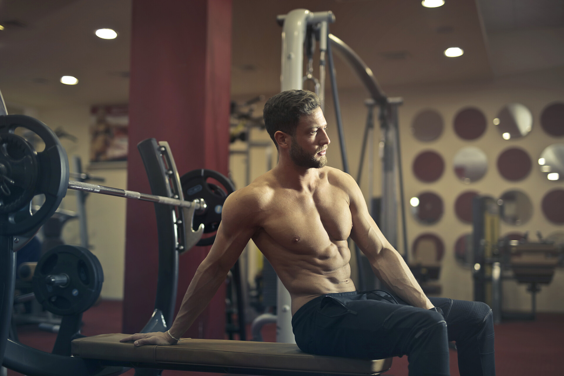 健身房运动健身房英俊半裸的男子坐在板凳上休息