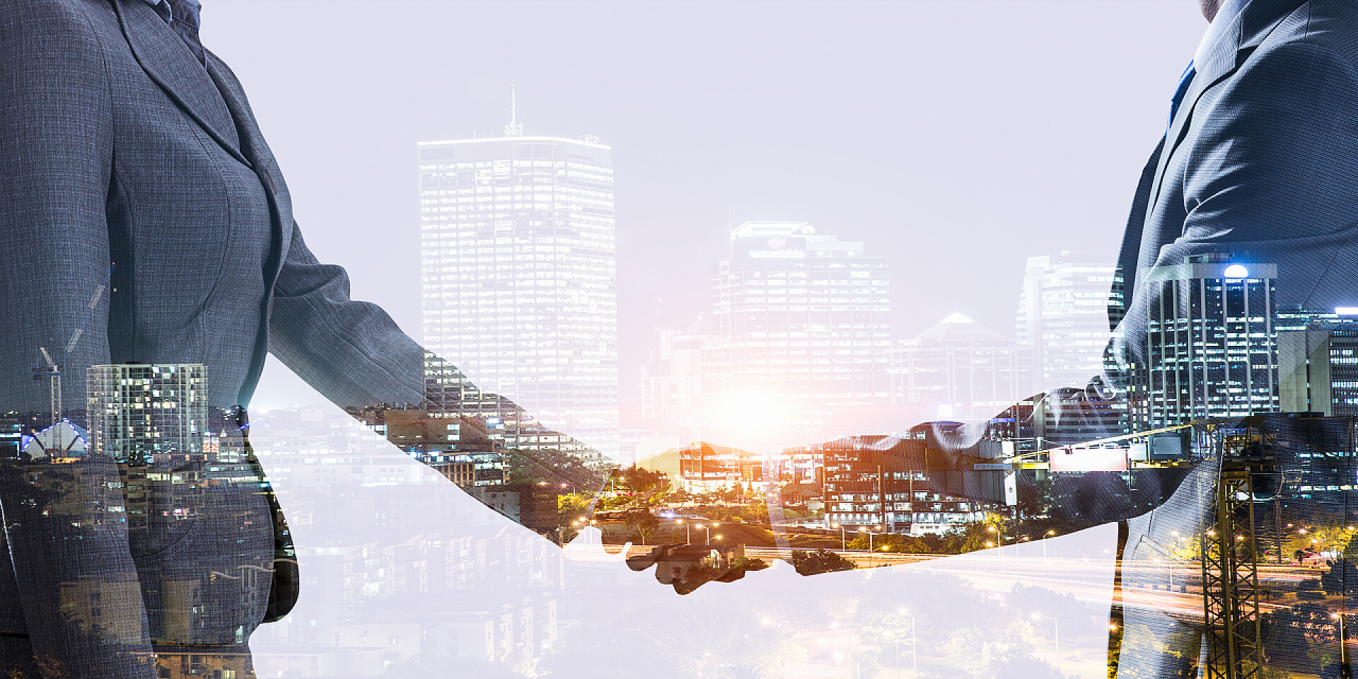 现代化城市背景中两个商业人士握手团队合作