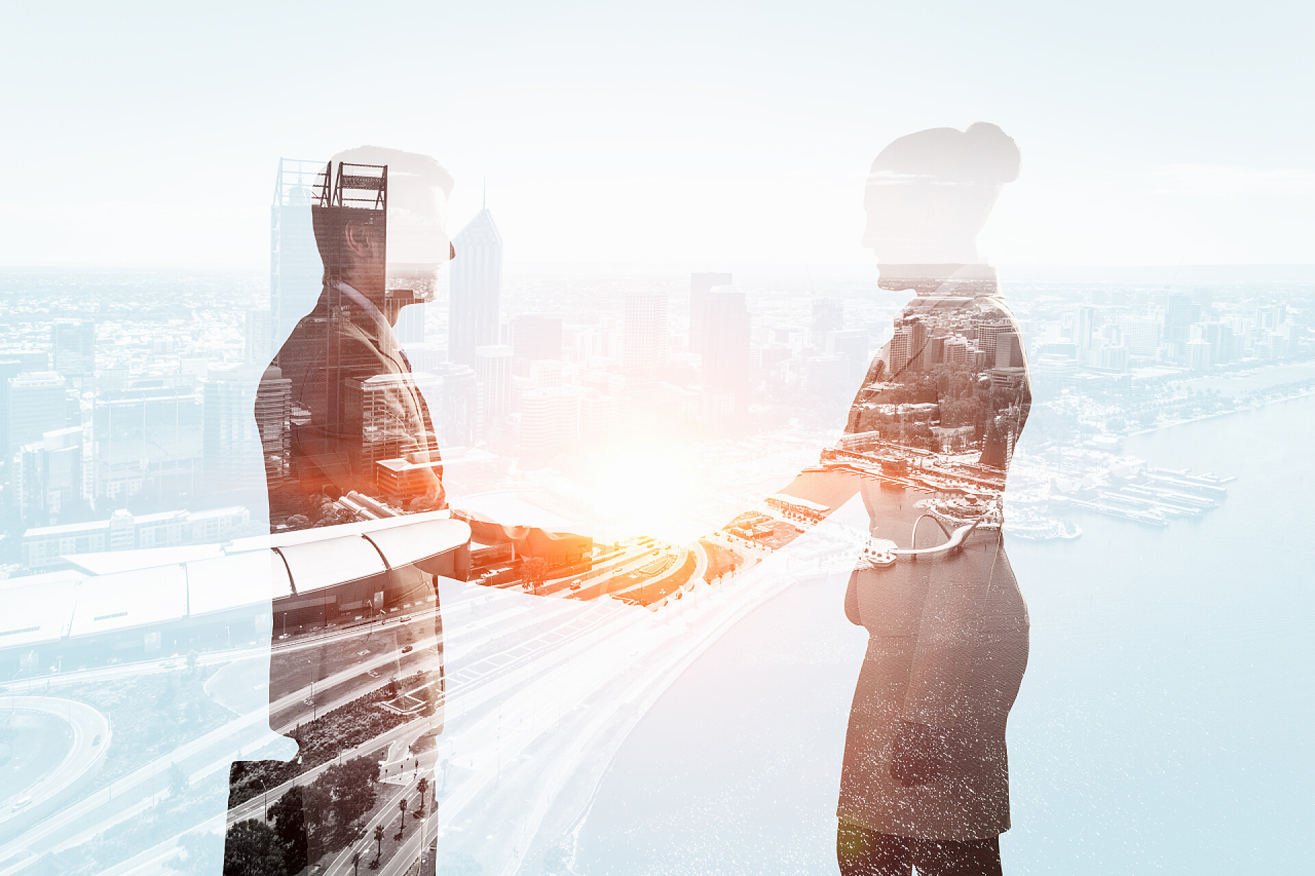 现代化城市背景中两个商业人士握手团队合作