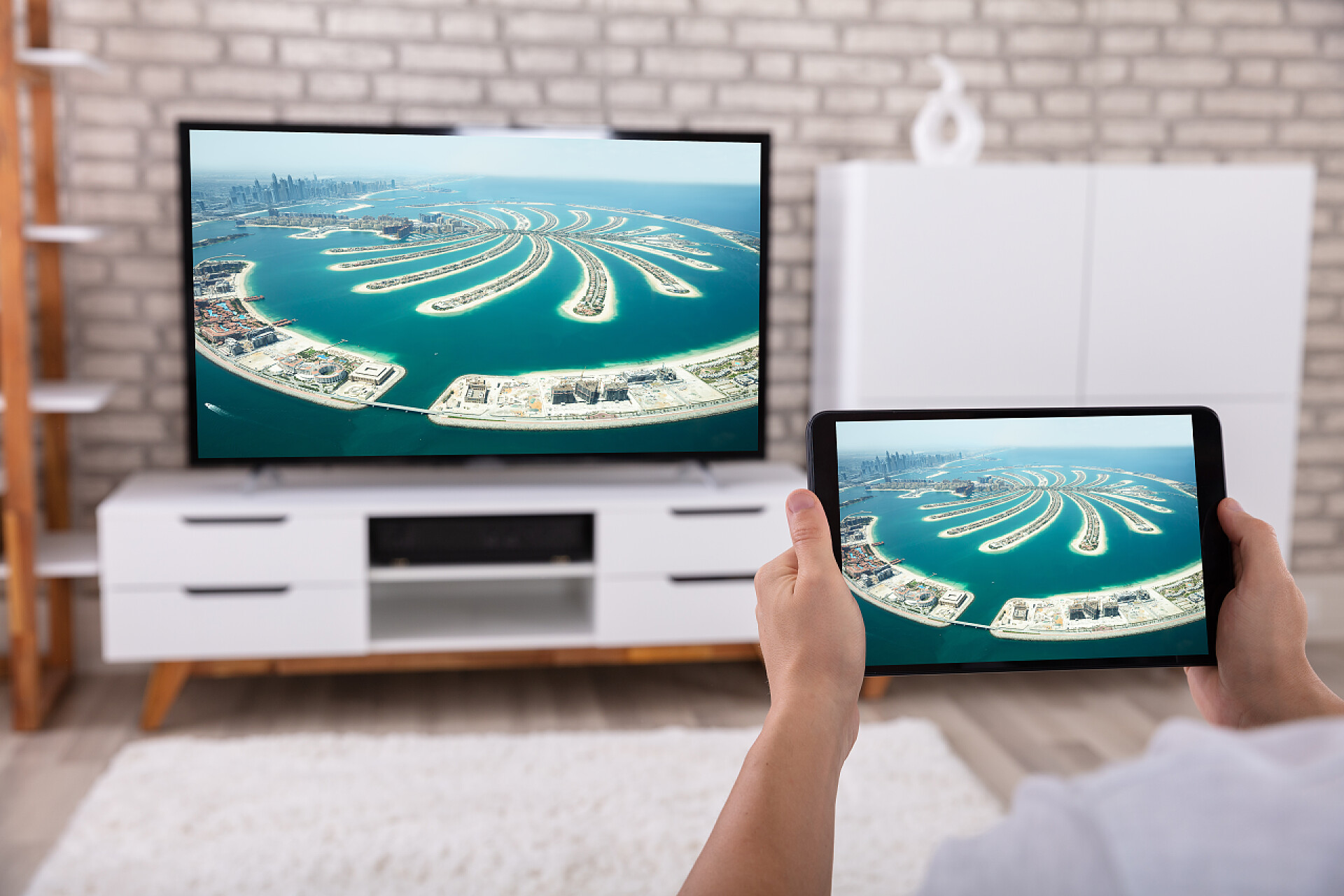 一个男人正在用平板投影到电视机上休闲娱乐