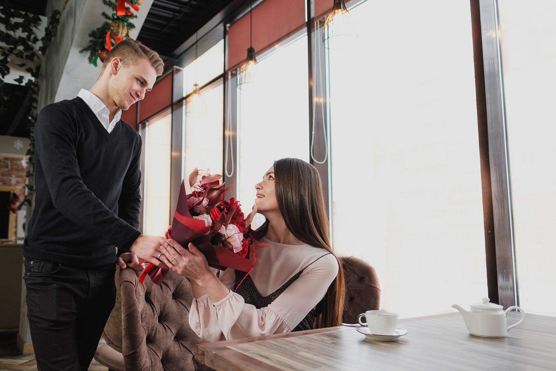餐厅里一个帅气的男人给女人送花节日庆祝