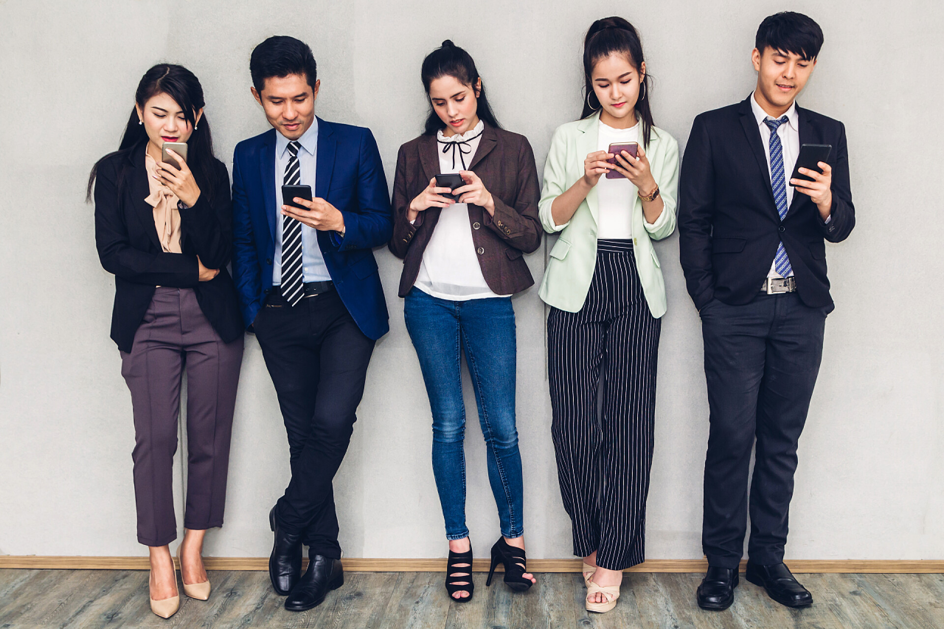 依靠在墙壁上玩手机的上班族