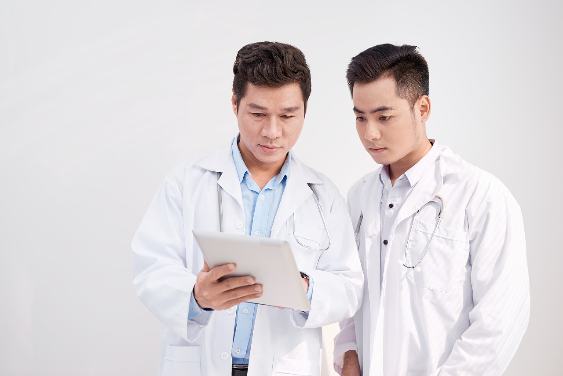 两名男子医生看着平板电脑并展开讨论医疗健康