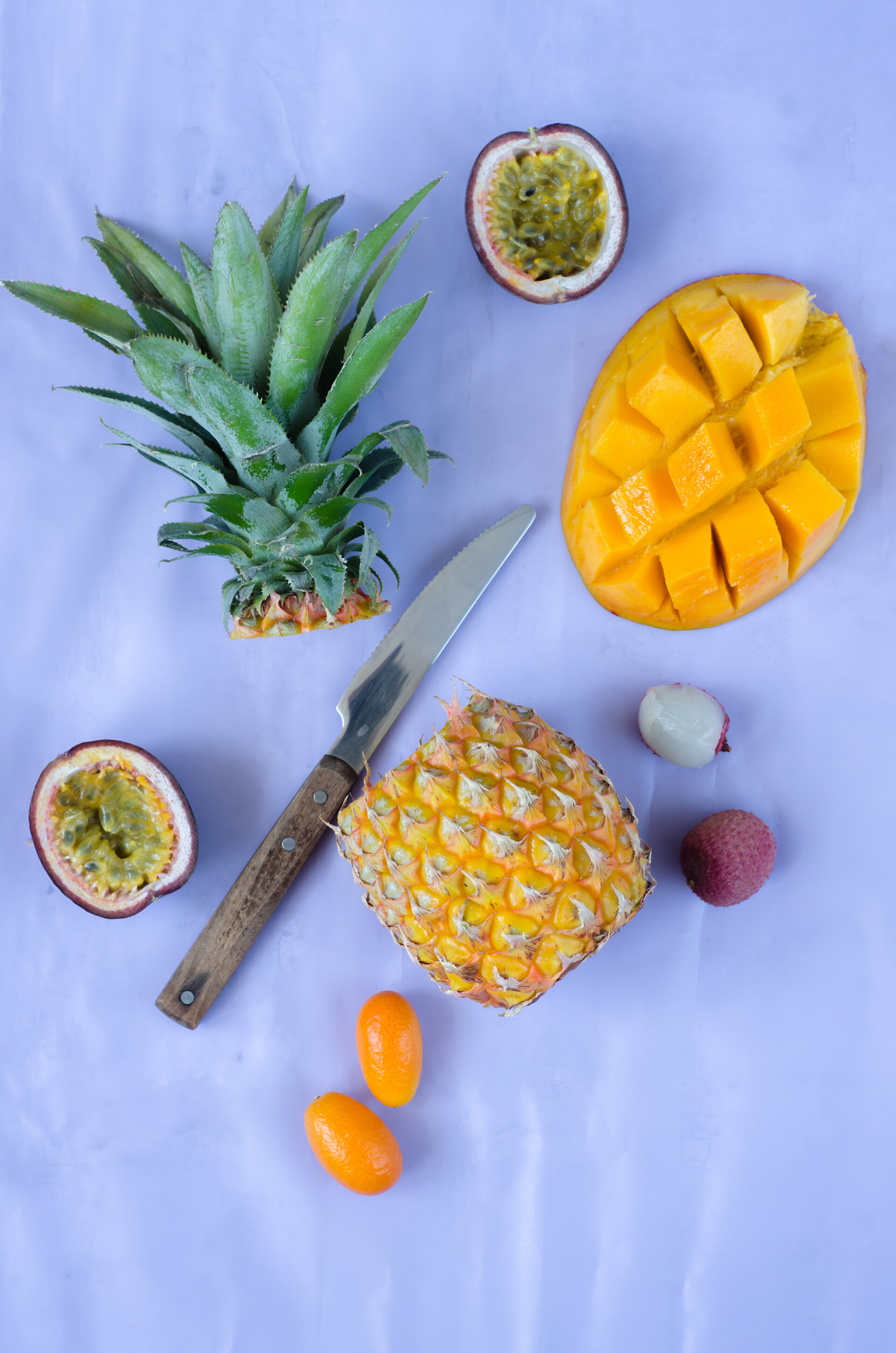 桌子上放着热带水果菠萝百香果荔枝芒果和小刀