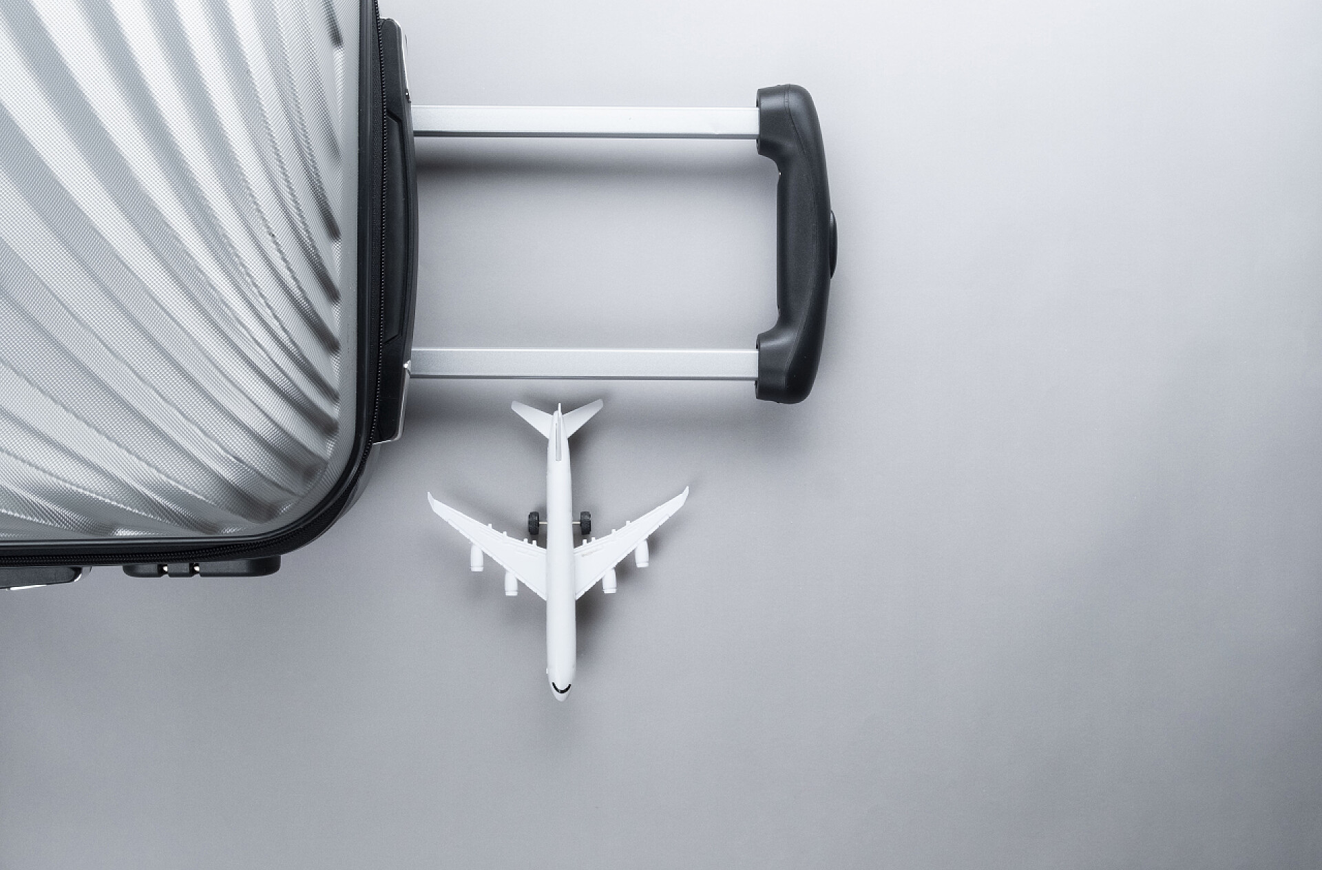 平躺灰色手提箱与迷你飞机旅行理念