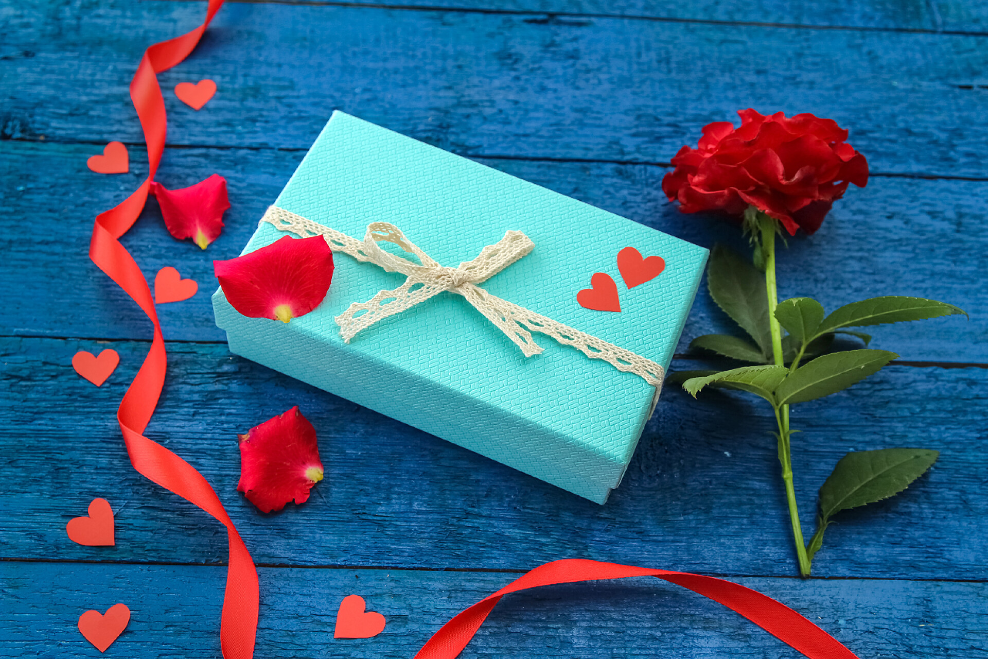 蓝色木板上的红丝带礼物盒玫瑰花礼品