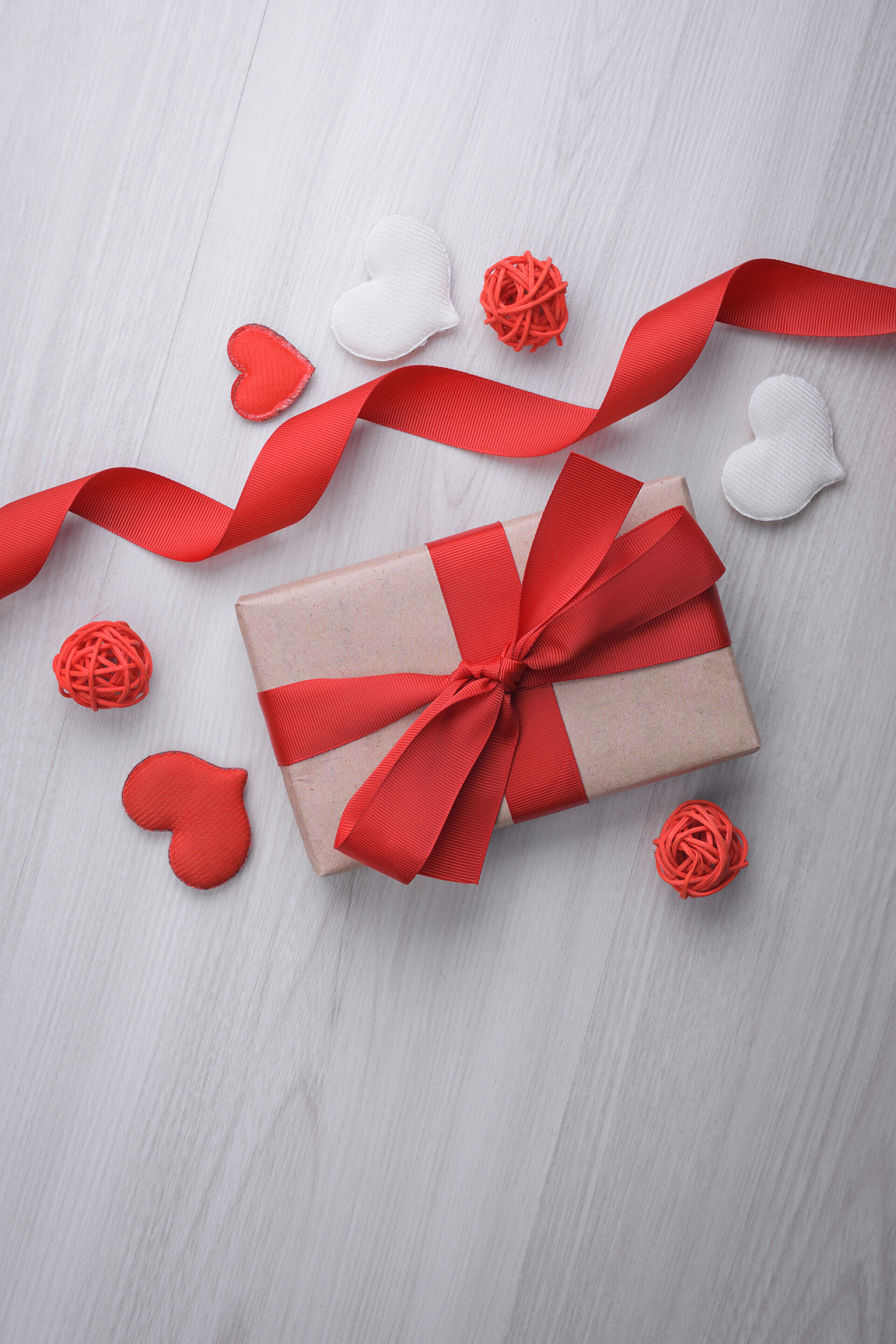 在灰色木纹背景上的情人节礼物礼盒爱心红丝带