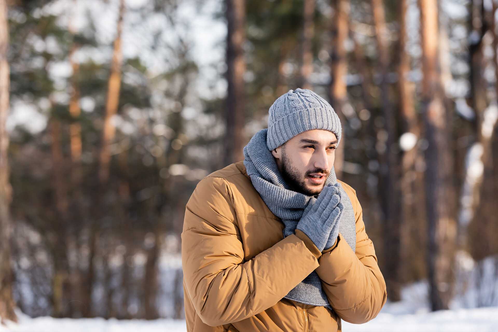 戴着手套和围巾的男人手搓手