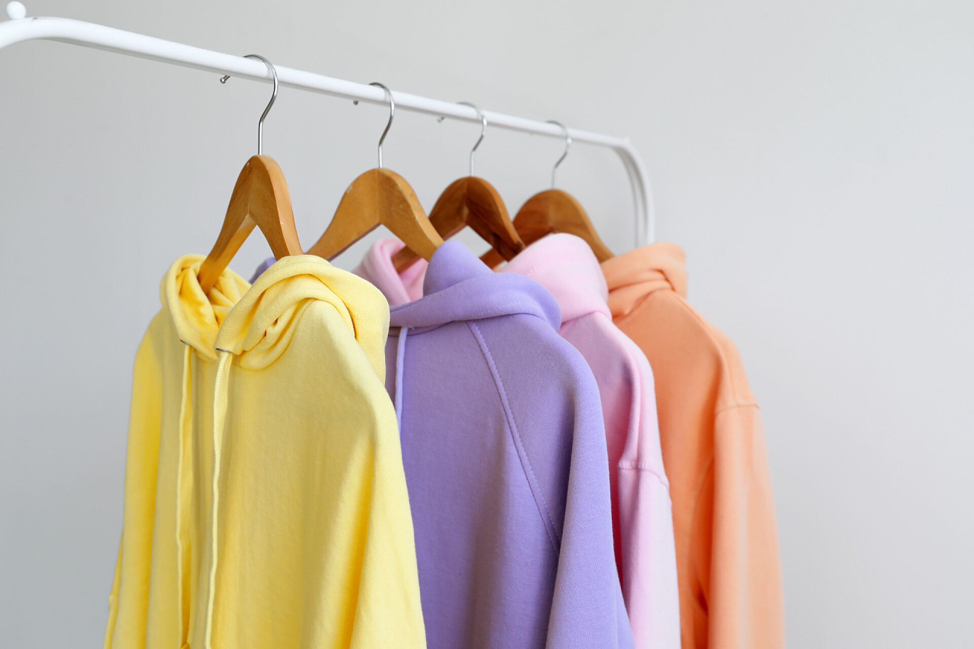 灰色背景上挂在衣架上的卫衣服装Rack