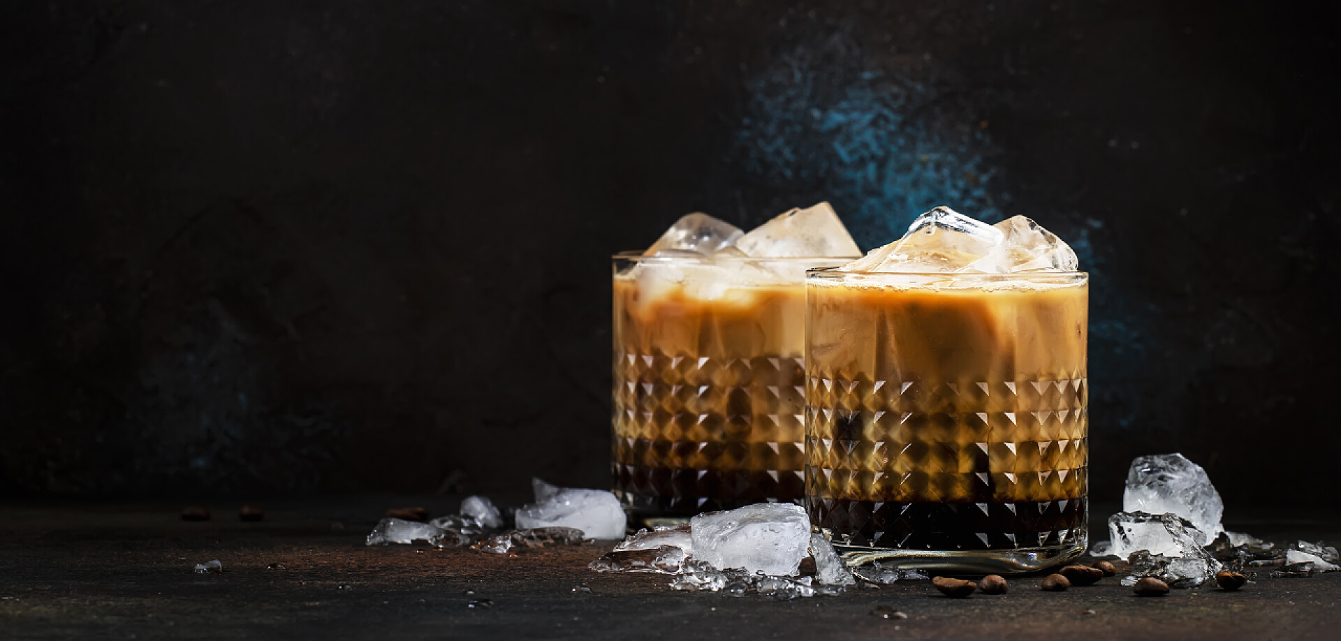 黑色背景上的两杯咖啡和冰块饮品，时髦的酒精饮料，伏特加，咖啡，奶油和冰块，深色背景，酒吧工具