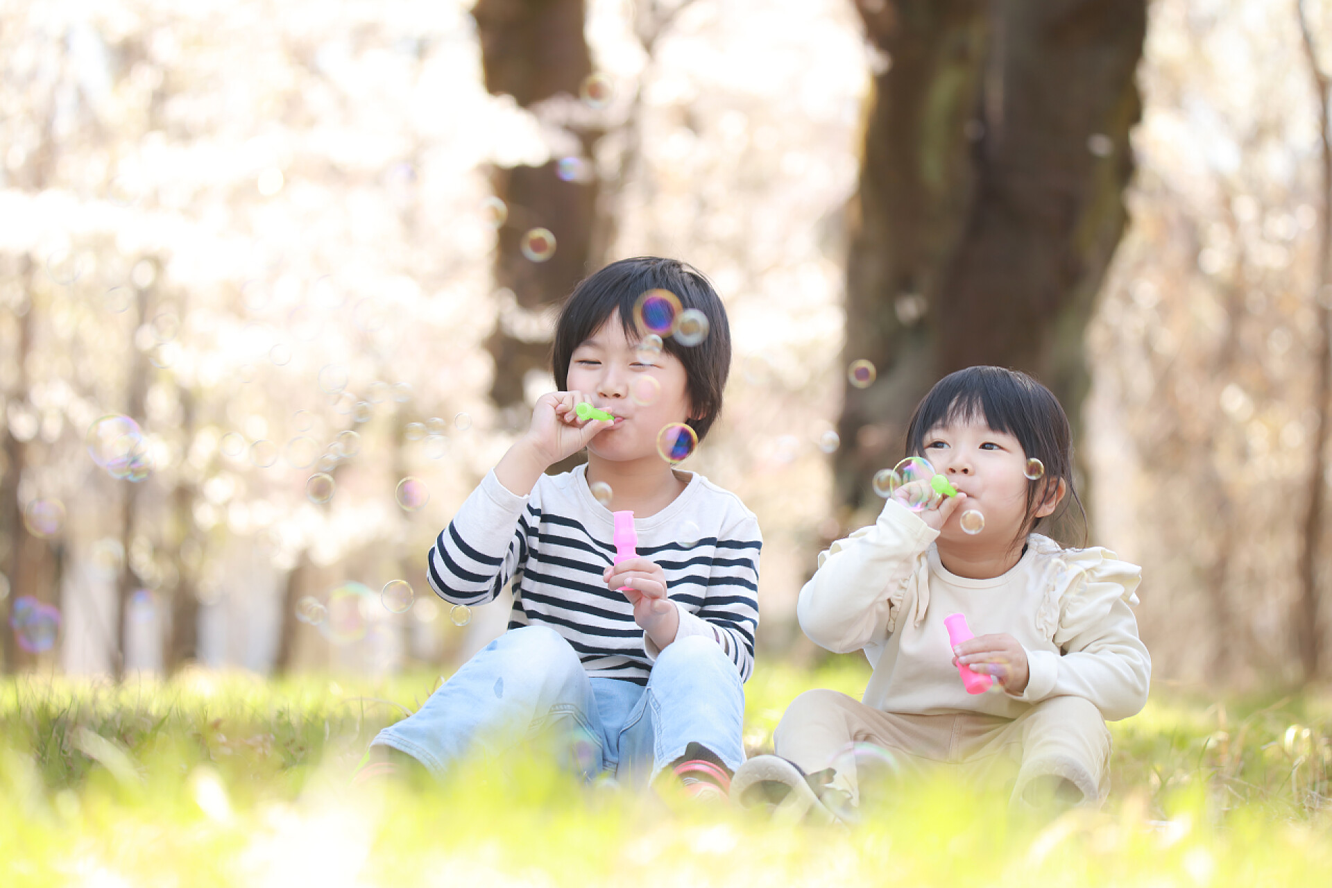 快乐的亚洲男孩和女孩在公园里吹泡泡