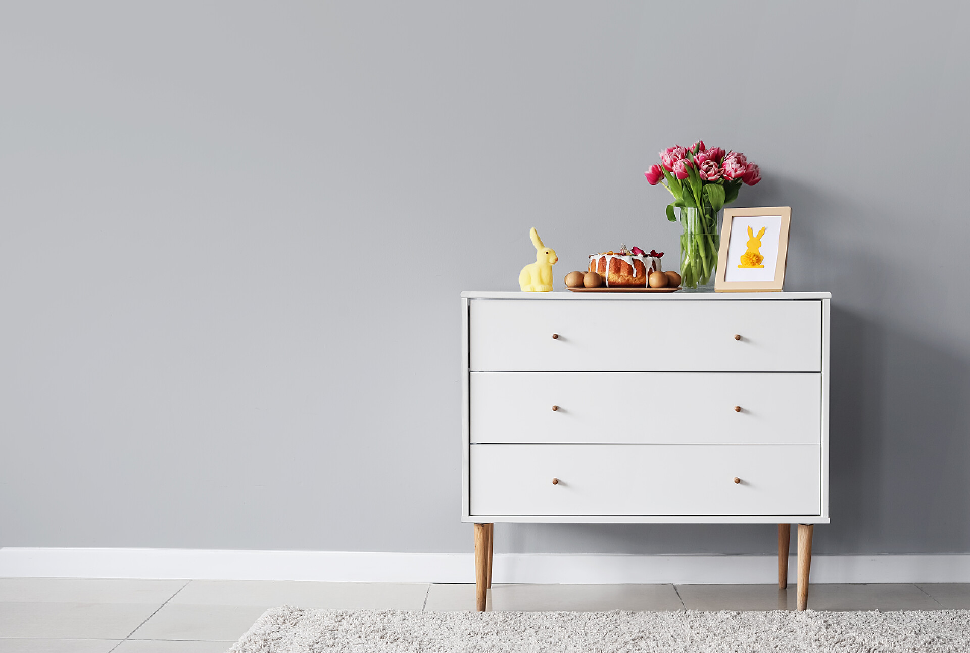 房间的墙边放着有鲜花和相片等的抽屉