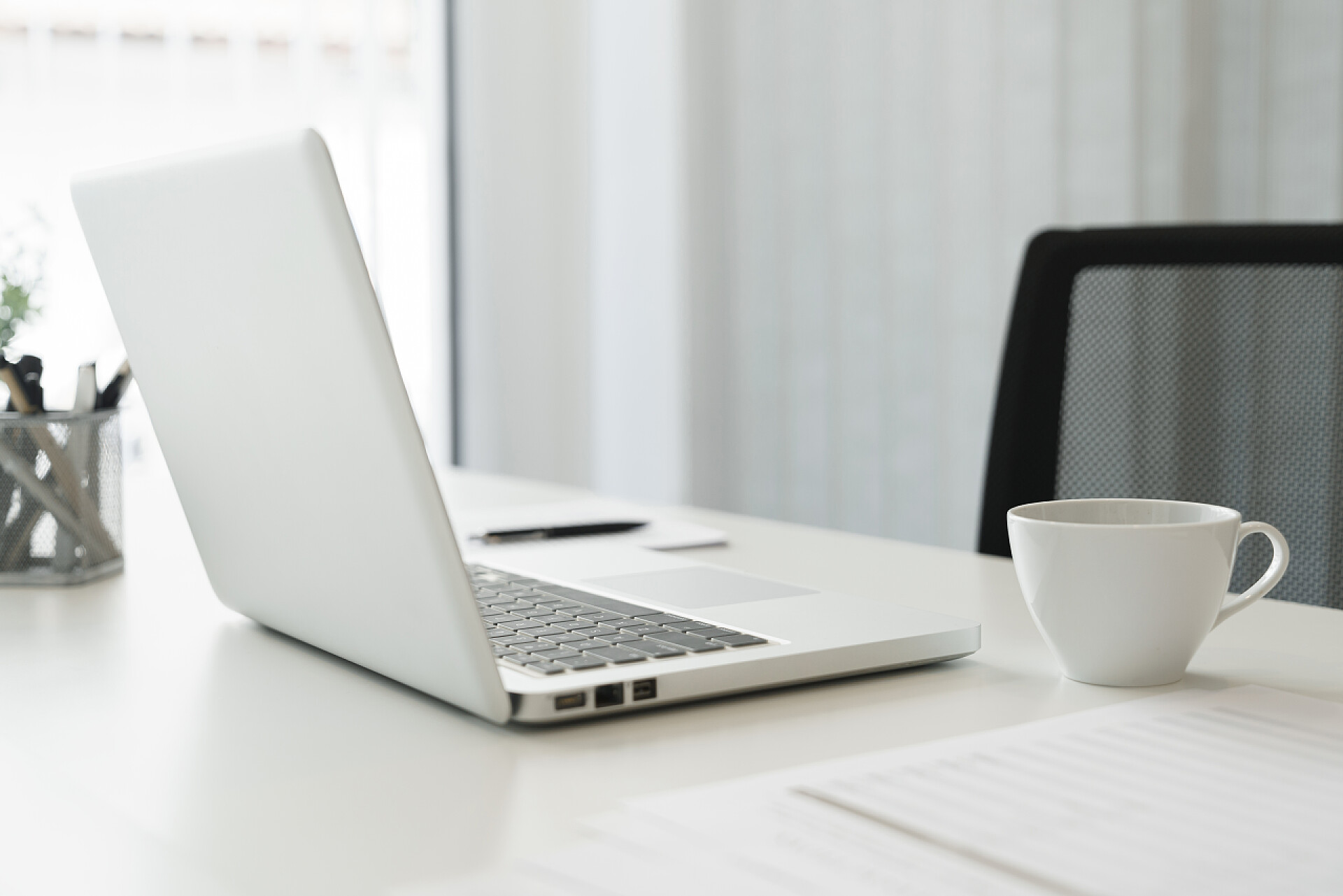 办公桌上放着笔记本电脑咖啡笔筒和文件现代化办公