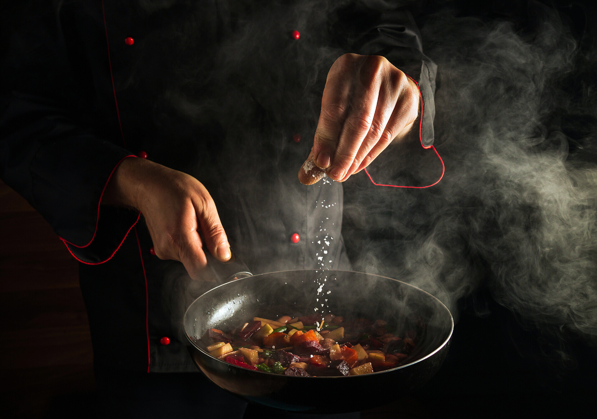 专业厨师在热腾腾的锅里加盐美食