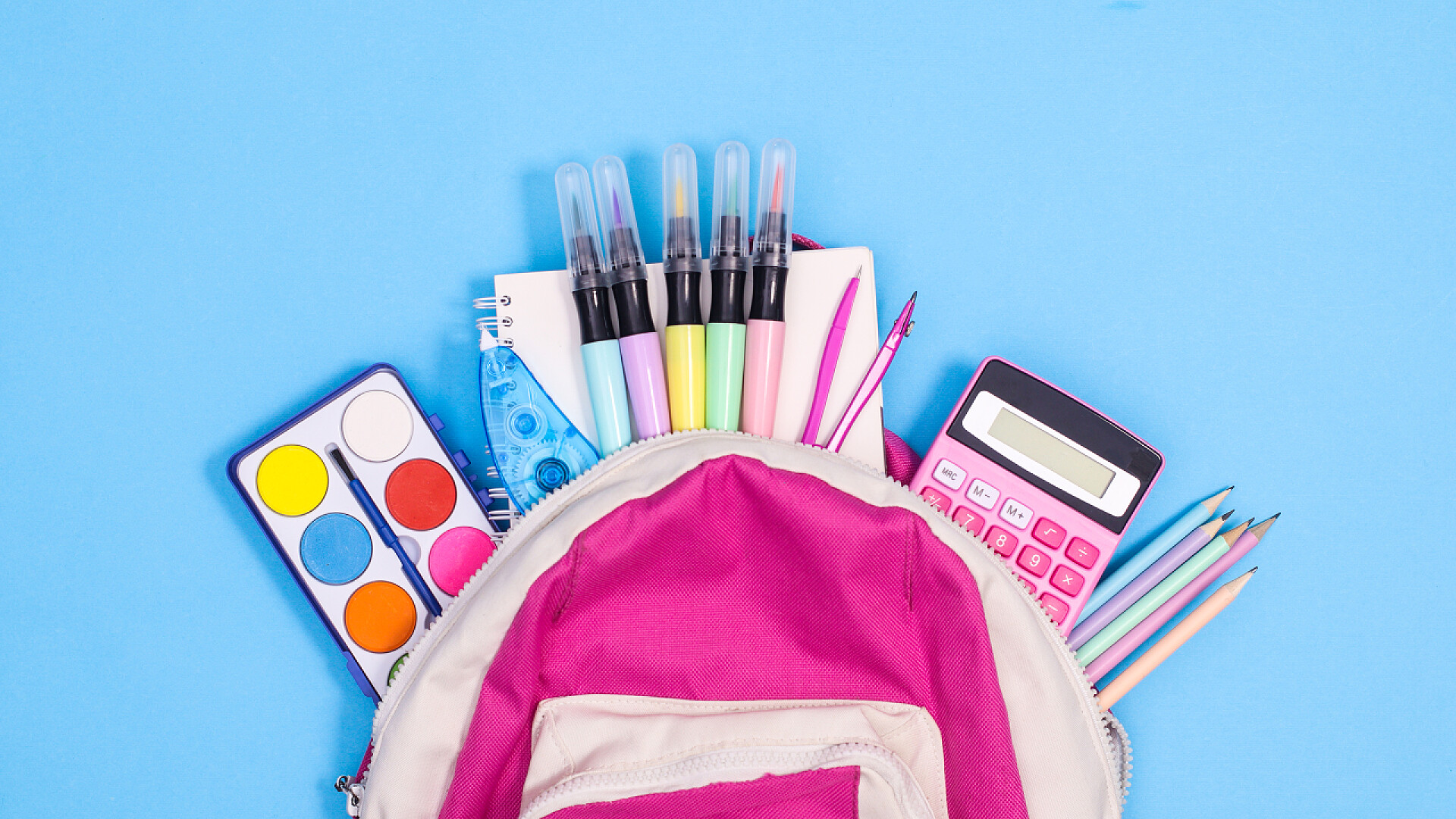 蓝色背景上粉色书包的学习文具