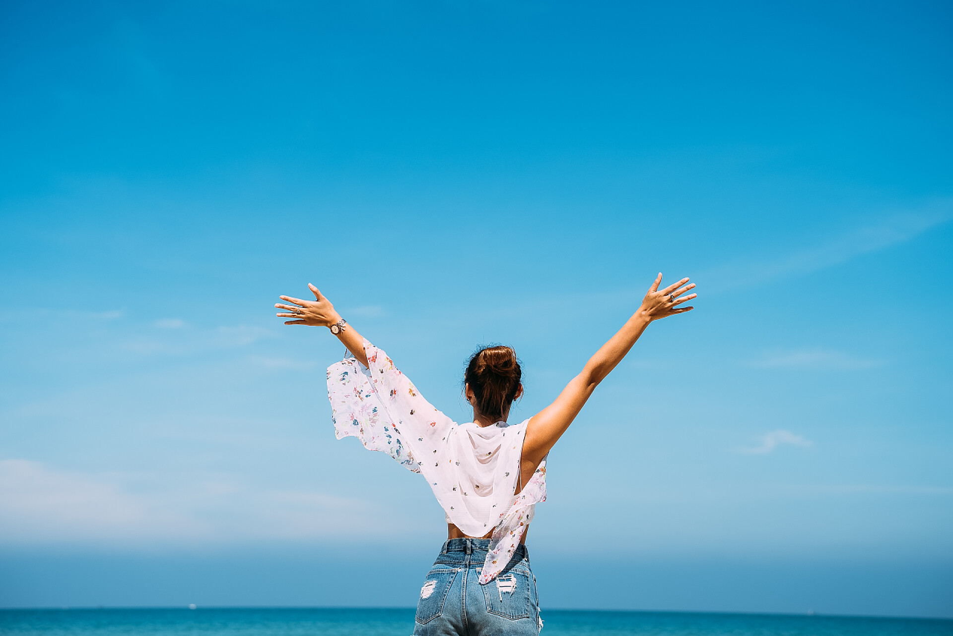 炎炎夏日女人张开双手欣赏着美丽的大海度假旅游