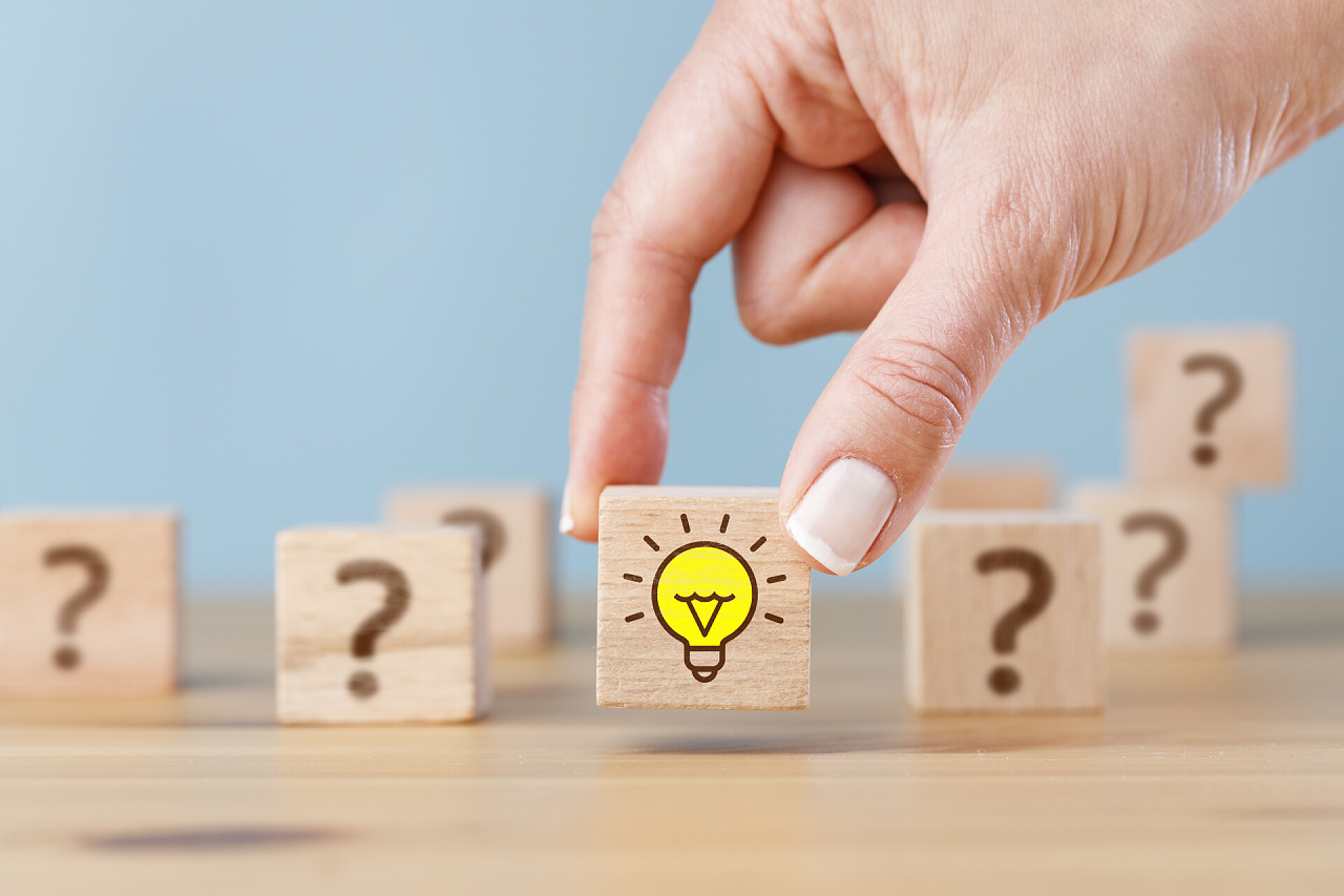 问题困惑女人手拿着灯泡图标和问号的木制立方体块