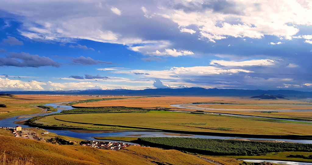夕阳的蓝天白云下甘肃唐克金色的草原上黄河拐了九道弯