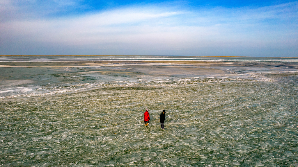 冬日青海湖畔游客站在冰面上