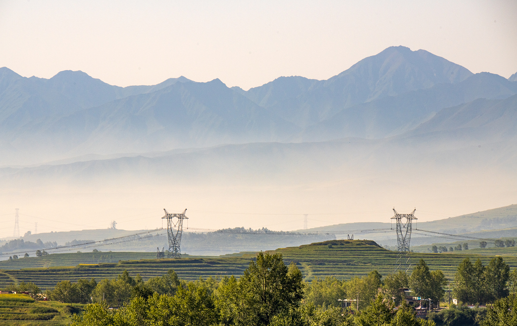 晨雾笼罩下的几座山峰和附近的输电线路