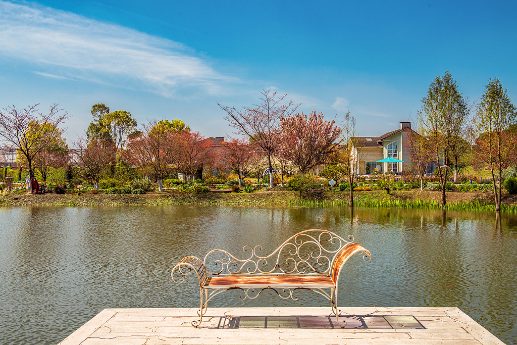 一处春天里河边的小镇和一把休闲的铁艺长凳