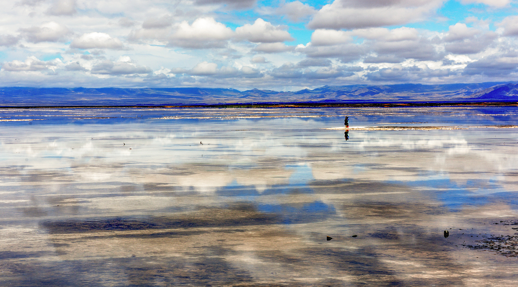 青海茶卡盐湖湖面上拍照的游客与天空的白云