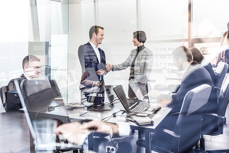 商务人士在现代化的公司办公室握手。