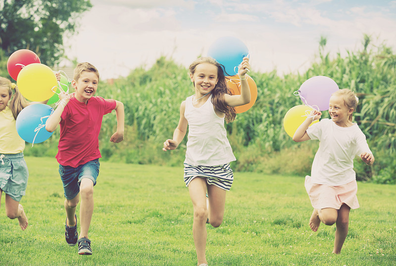 孩子们在公园里拿着气球奔跑