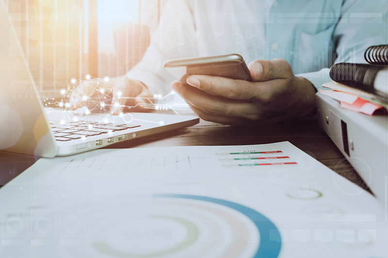 晨光中，商人将手提电脑放在办公室的木桌上。复古的效果