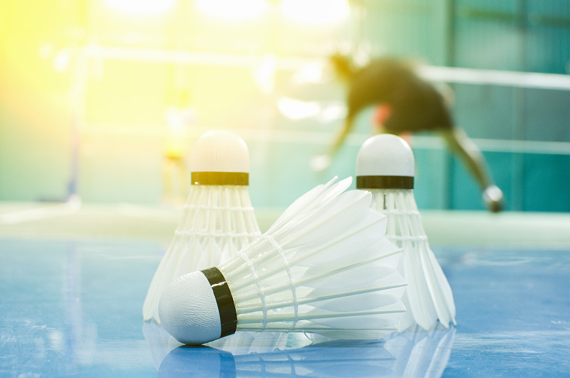 与羽毛球运动员一起在球场的地板上踢毽子