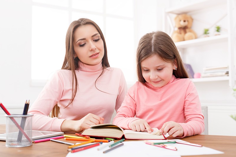 妈妈在帮助女儿做家庭作业。