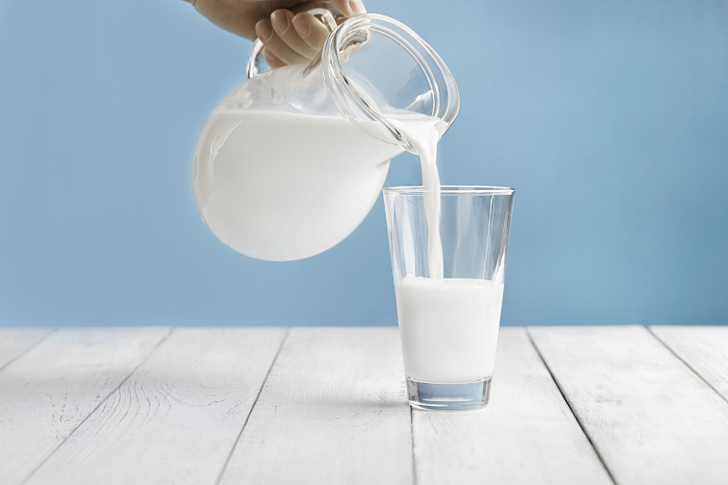 牛奶从壶里倒进玻璃杯里。开菲尔或蔬菜，坚果奶的替代品。文本的地方