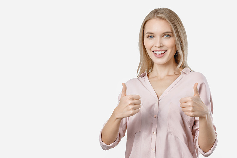 开朗年轻的金发女子显示拇指孤立在白色的背景