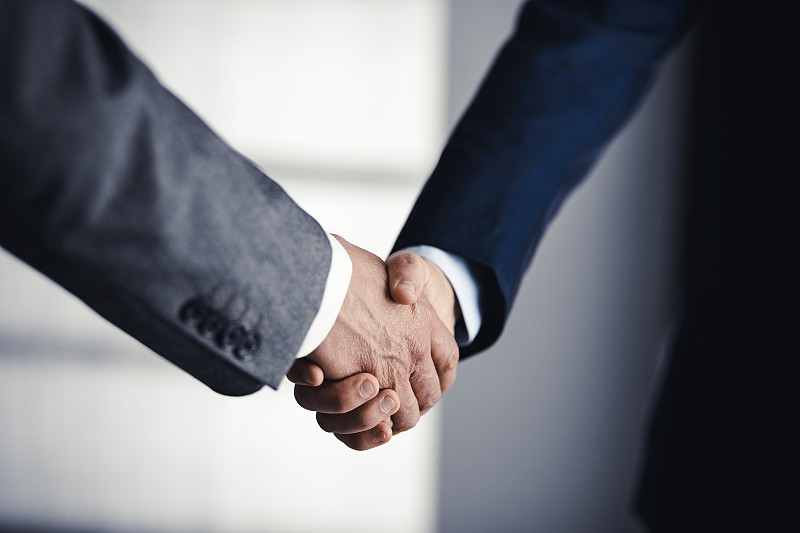 商务人士穿着西装站着握手，特写。商务沟通的概念。握手和营销