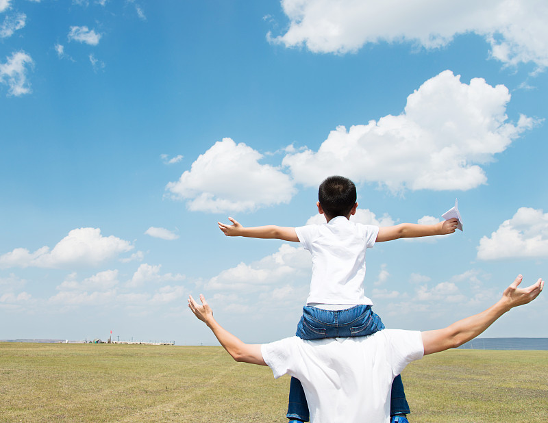儿子和父亲在田野里玩纸飞机