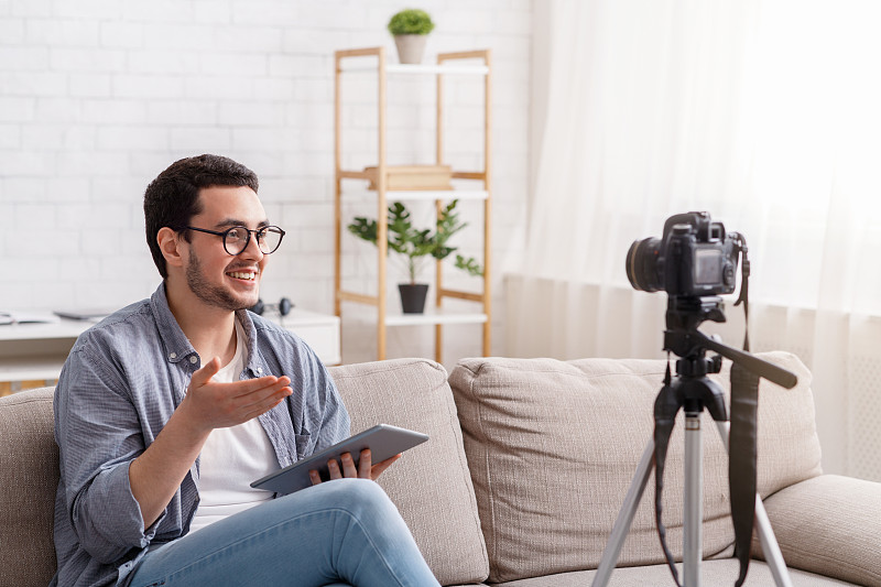 自信的年轻人用摄像机记录博客。热情地说