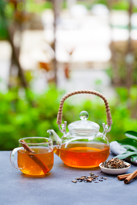 夏日户外背景上的玻璃杯和茶壶中的茶。副本的空间。