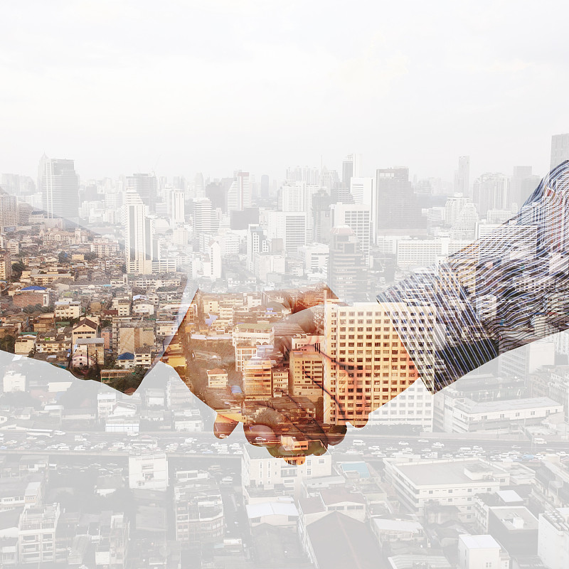 双曝光握手与夜色城市模糊的背景。