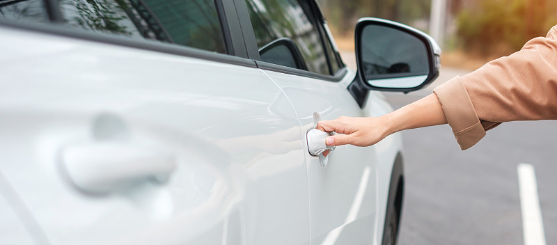 手握智能汽车把手，打开车门。交通、旅游、服务及汽车租赁概念