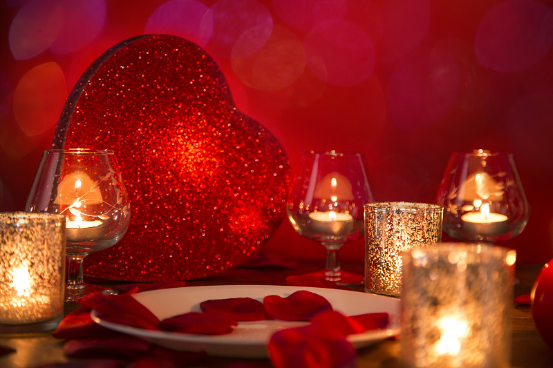 情人节的浪漫烛光晚餐与心和玫瑰花瓣。