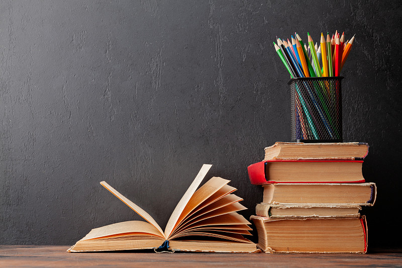 旧书放在木桌和黑板上