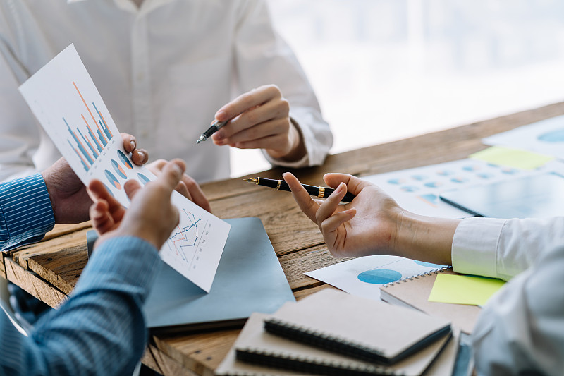 业务团队在会议上一起计划投资。近距离观察商务人士顾问指着图表和分析财务报告。