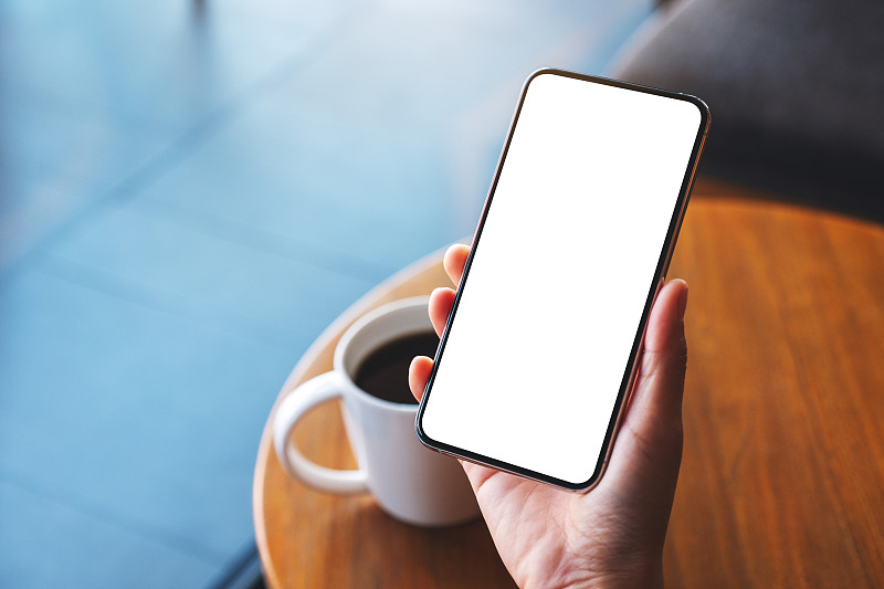 一个女人拿着手机和空白的白色桌面屏幕