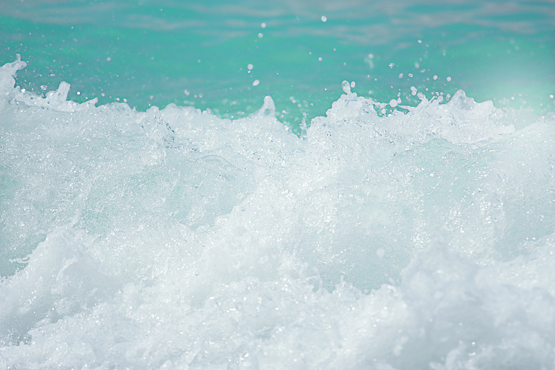 海浪拍打着海岸，激起水和白色的泡沫。