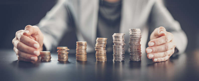 一个女人坐在桌子旁，手牵着手围着一列硬币。