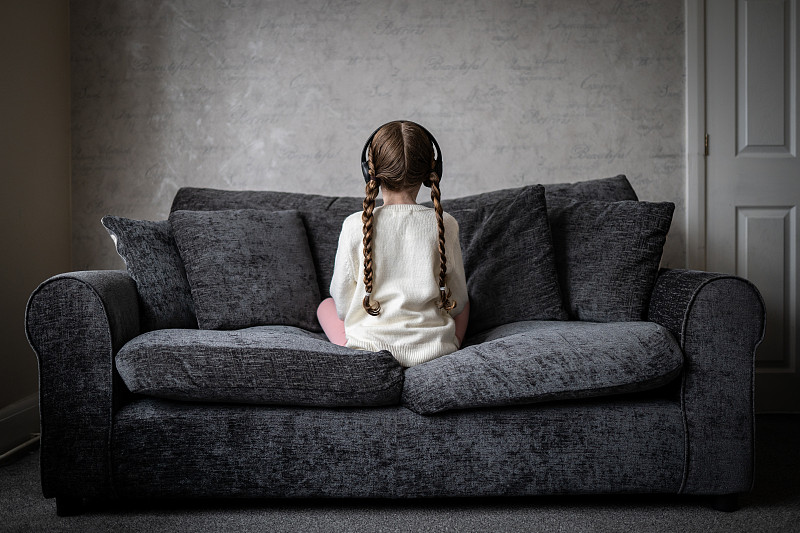 患有自闭症的小女孩独自坐在黑暗忧郁的房间里，看着远离镜头的阴影