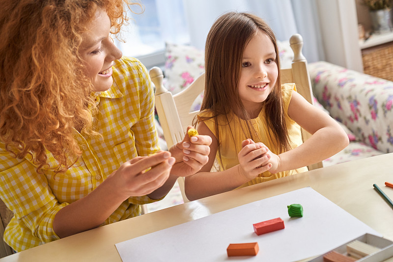 成年母亲和她的小女儿在玩橡皮泥