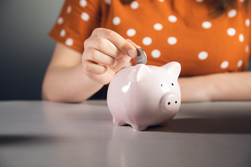 女人把硬币放进储蓄罐